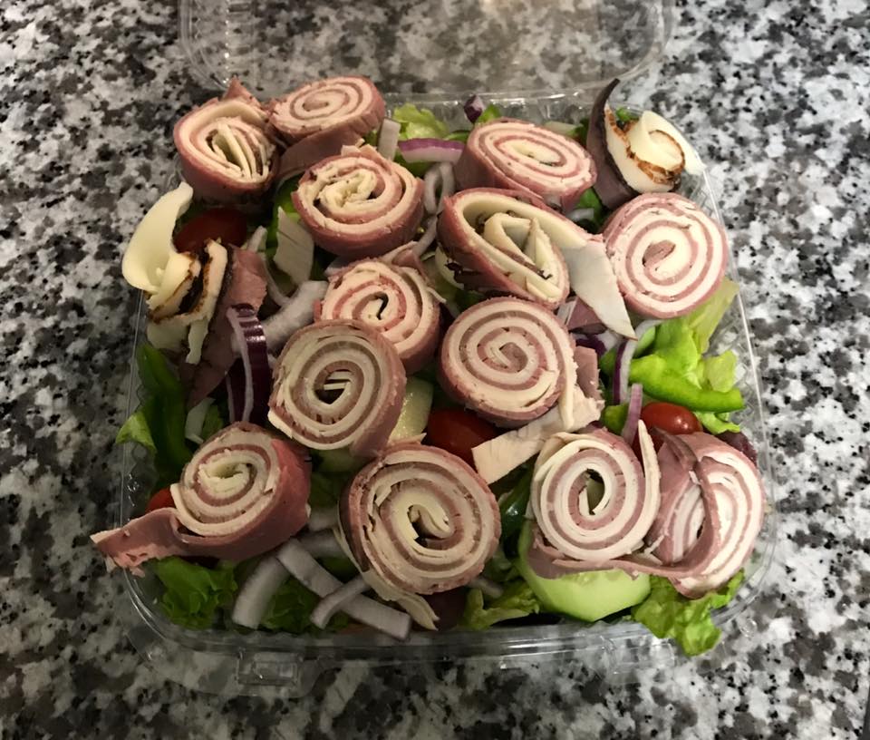 A close up of a salad in a plastic container on a table.