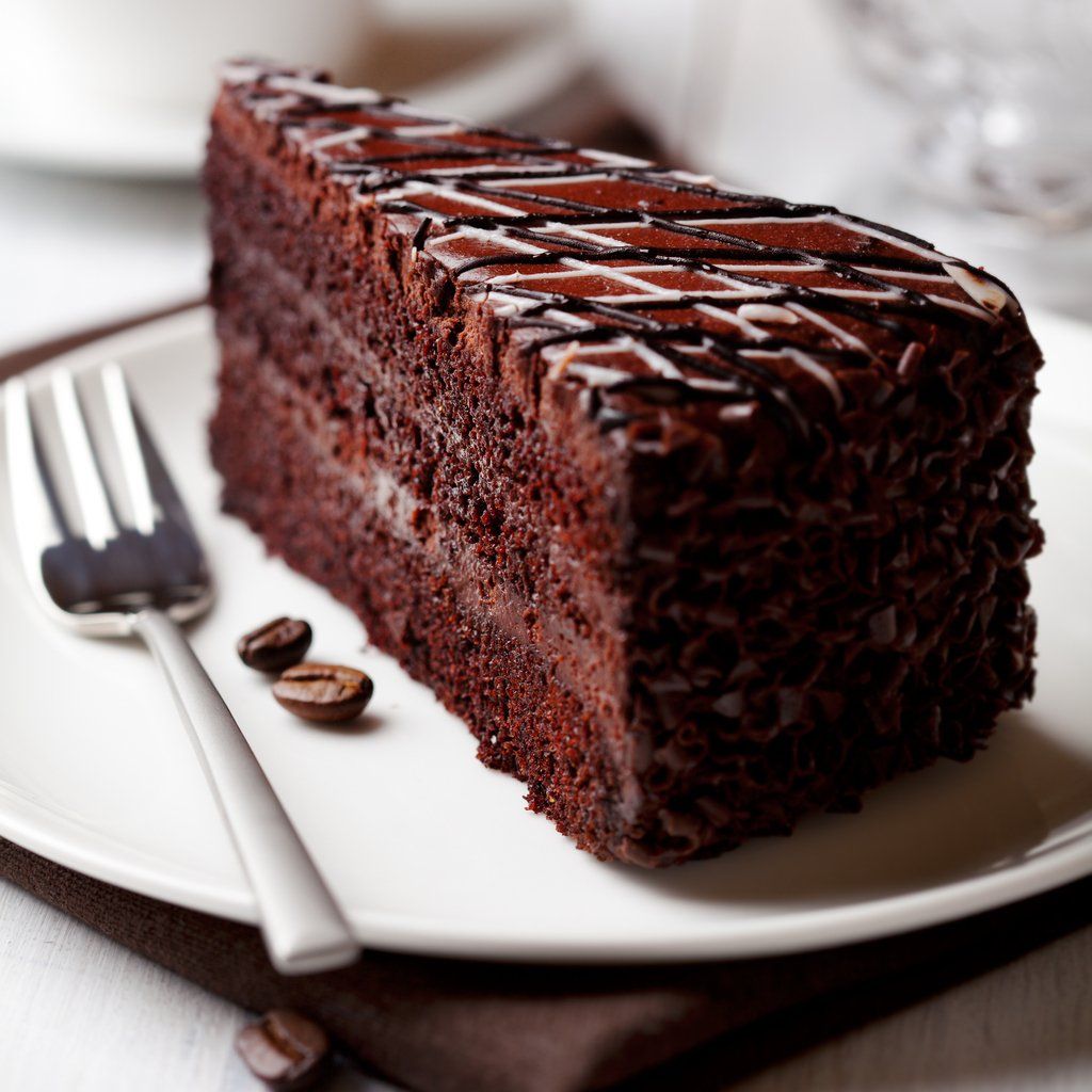 A slice of chocolate cake on a white plate with a fork
