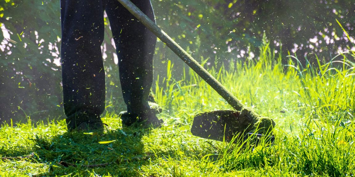 A man is mowing the grass with a lawn mower.