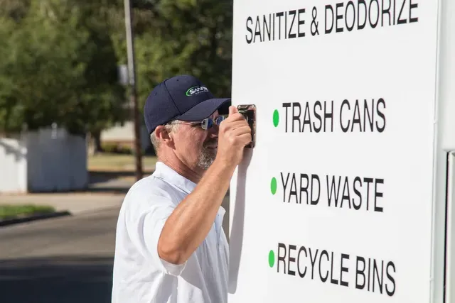 Man in a hat adjusting sign that reads
