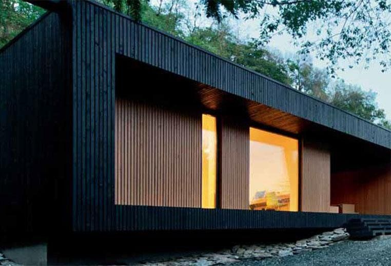 parete abitazione in legno nero, con infissi vetrati