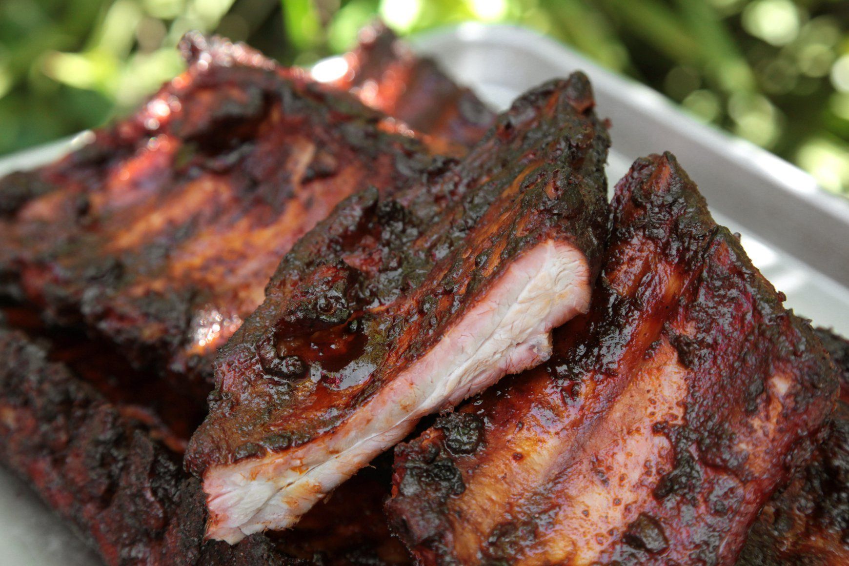 Grilled barbecue ribs stacked on a plate, charred and glazed with sauce