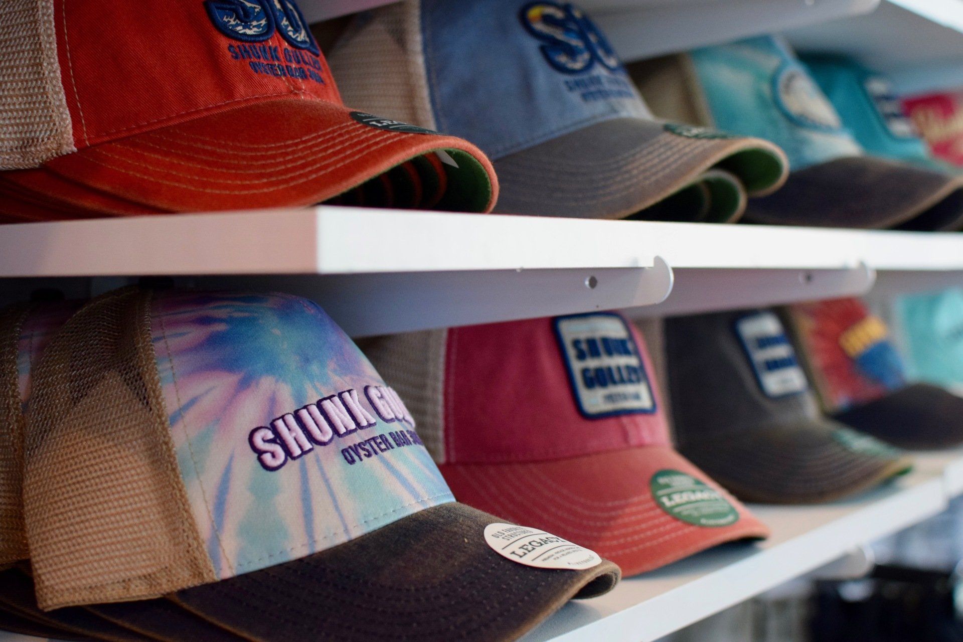Rows of colorful trucker hats on white shelves in a store, including orange, tan, blue, and red caps