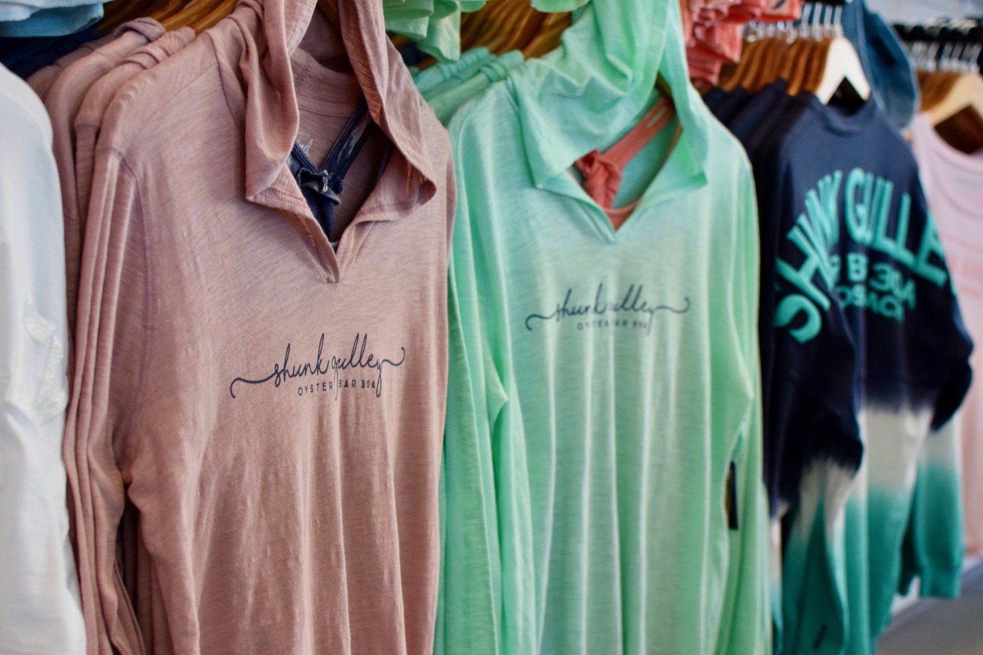 Pastel collared shirts hanging on a rack, including pink, mint green, and navy