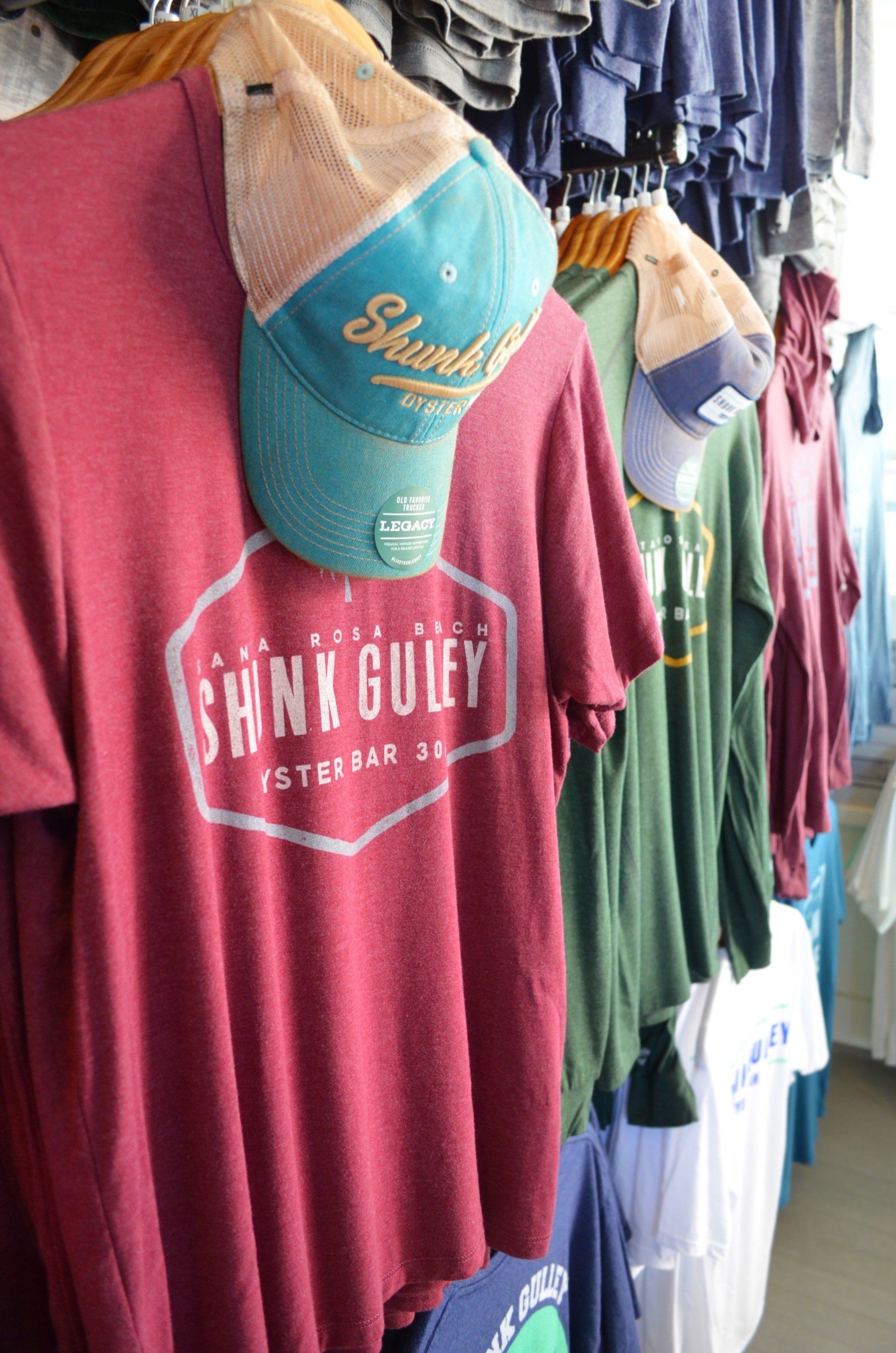 Racks of colorful T-shirts and hats hanging in a clothing store