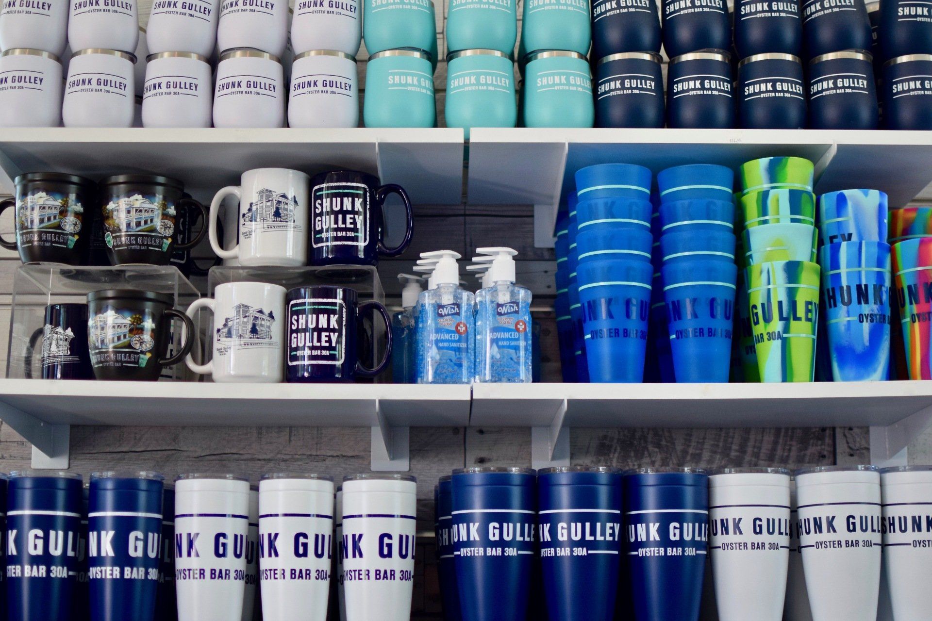 Shelved drink cups and tumblers in black, white, blue, and green with bold graphics.