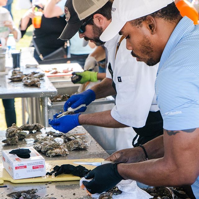People shucking oysters at a seafood table during an outdoor event