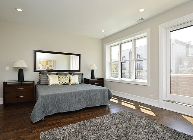 Bedroom with large bed, wood floors, and a large window