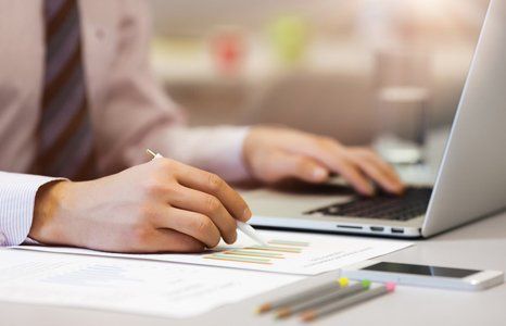 Business Person in Shirt and Tie reading Data Chart on printed Media