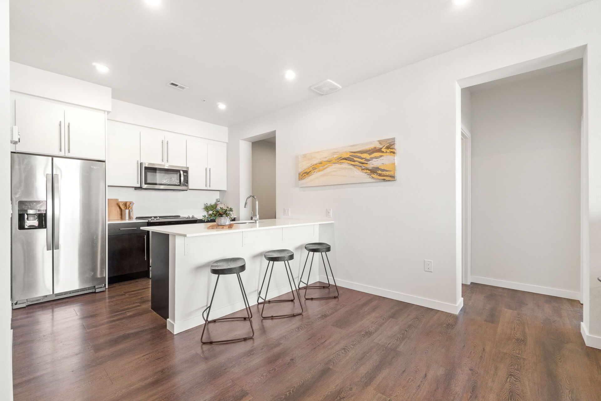 Modern kitchen with white cabinets, stainless steel appliances, and a breakfast bar.