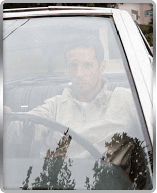 For windscreen replacements in Yorkshire call Nationwide Windscreens (York) Ltd man behind windscreen sat in driving seat of a car