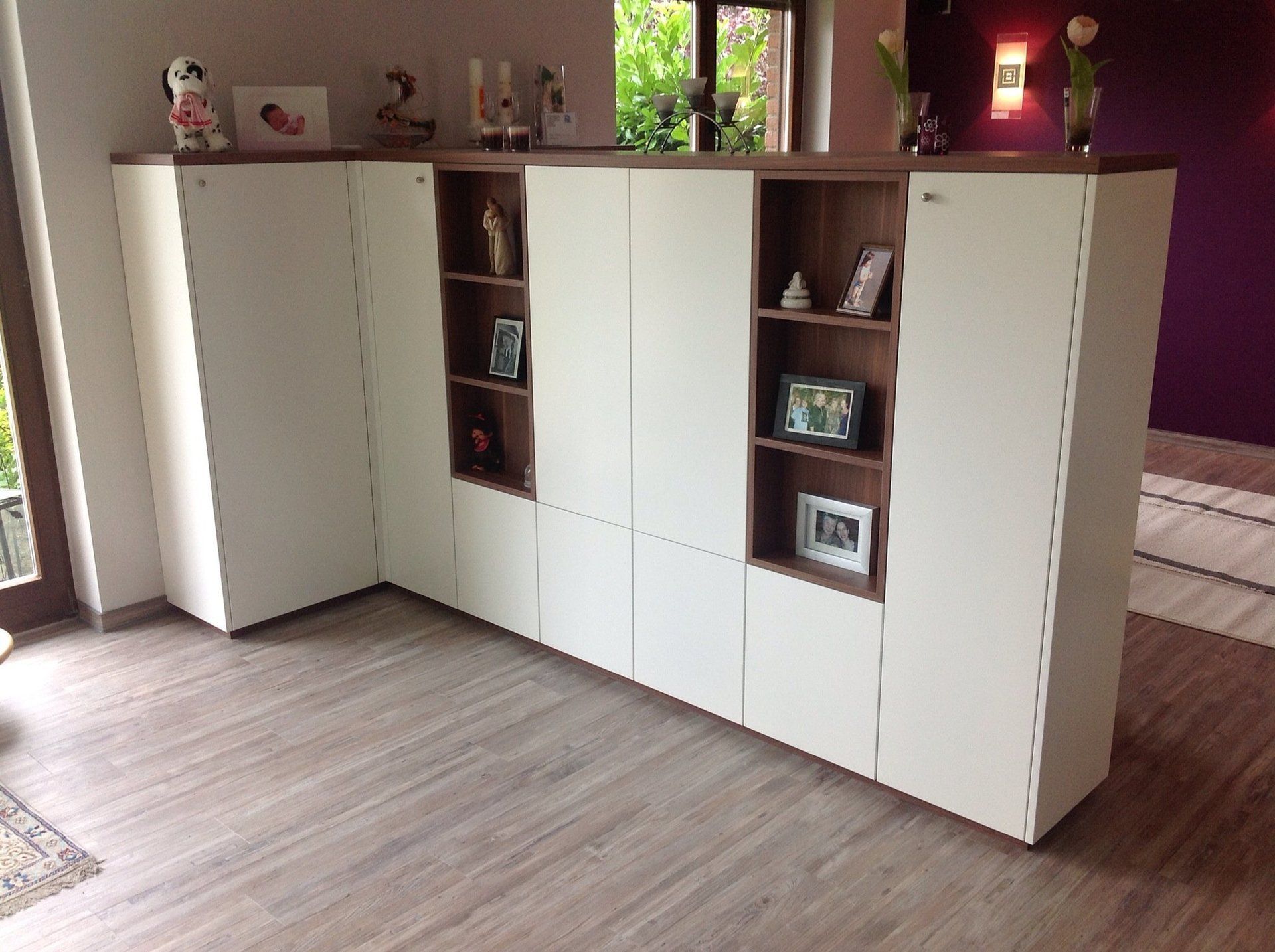 Ein Wohnzimmer mit weißen Schränken und Holzregalen