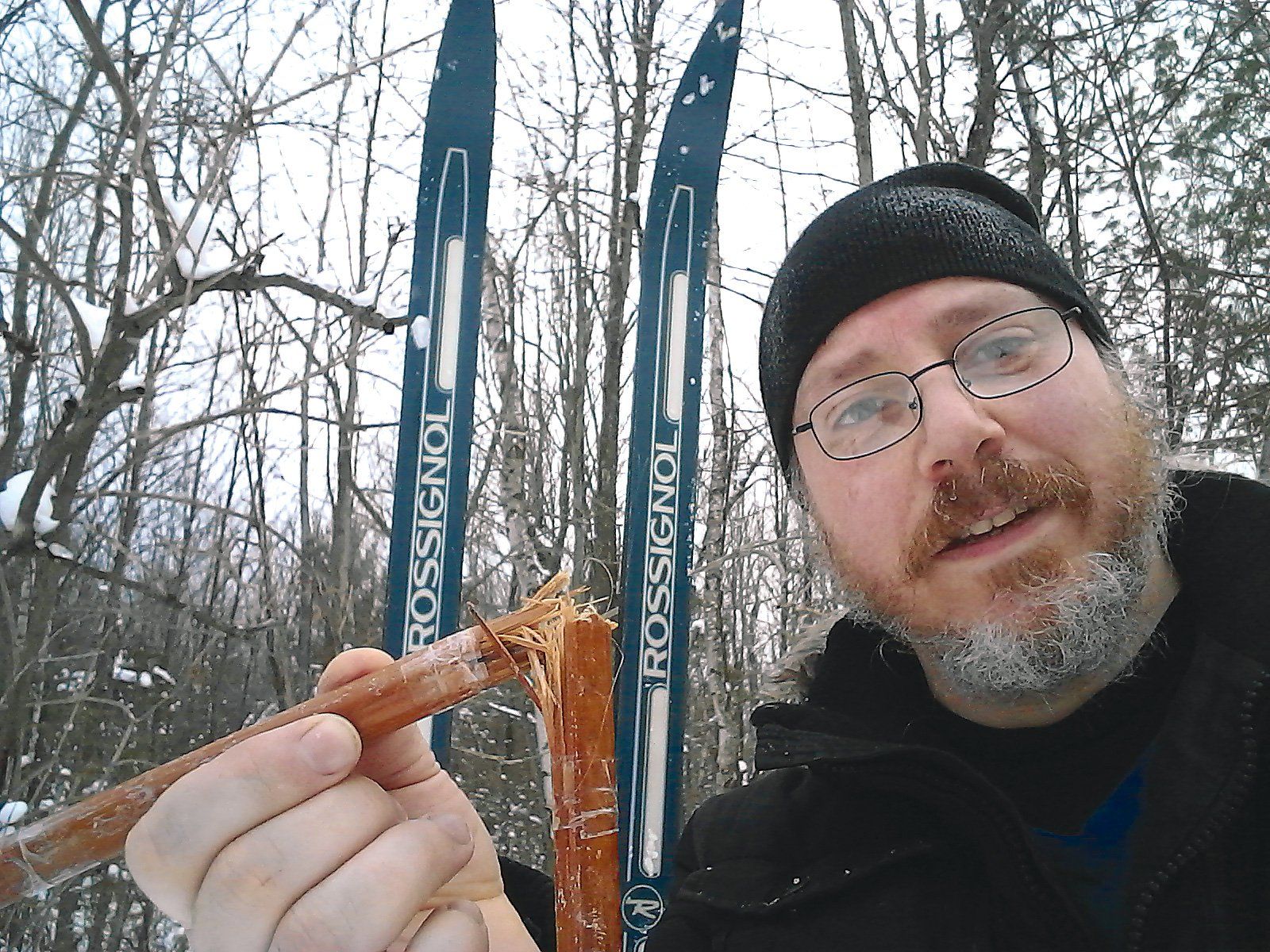 Alec McElcheran showing his broken stick with his skis planted in the snow behind him
