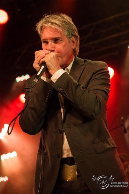 Guy Bélanger, avec un air distingué jouant son harmonica.