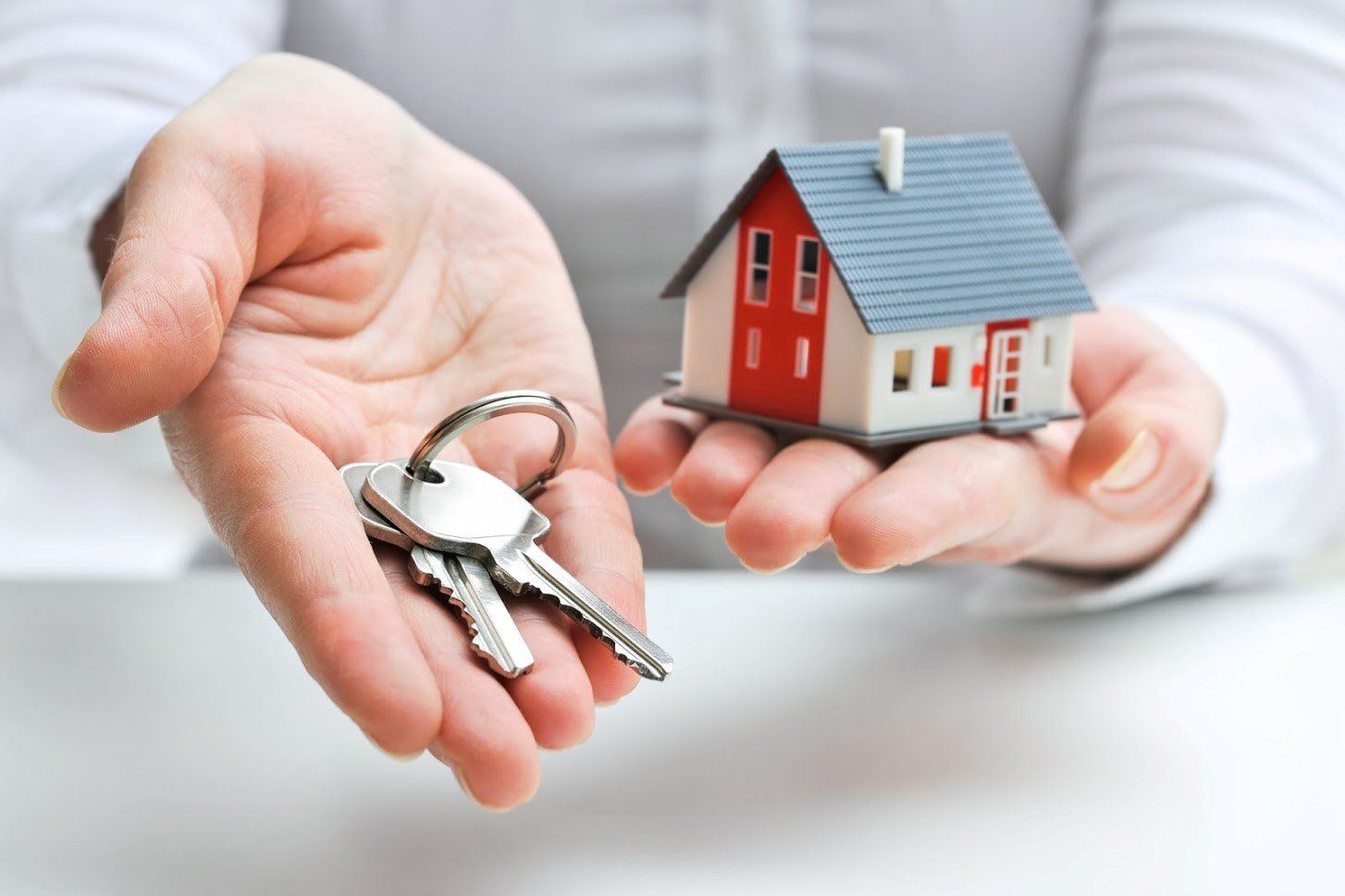 Man Holding Key and House Model — Houston, TX — Dixie Safe & Lock Service Inc. Man Holding Key and House Model — Houston, TX — Dixie Safe & Lock Service Inc.