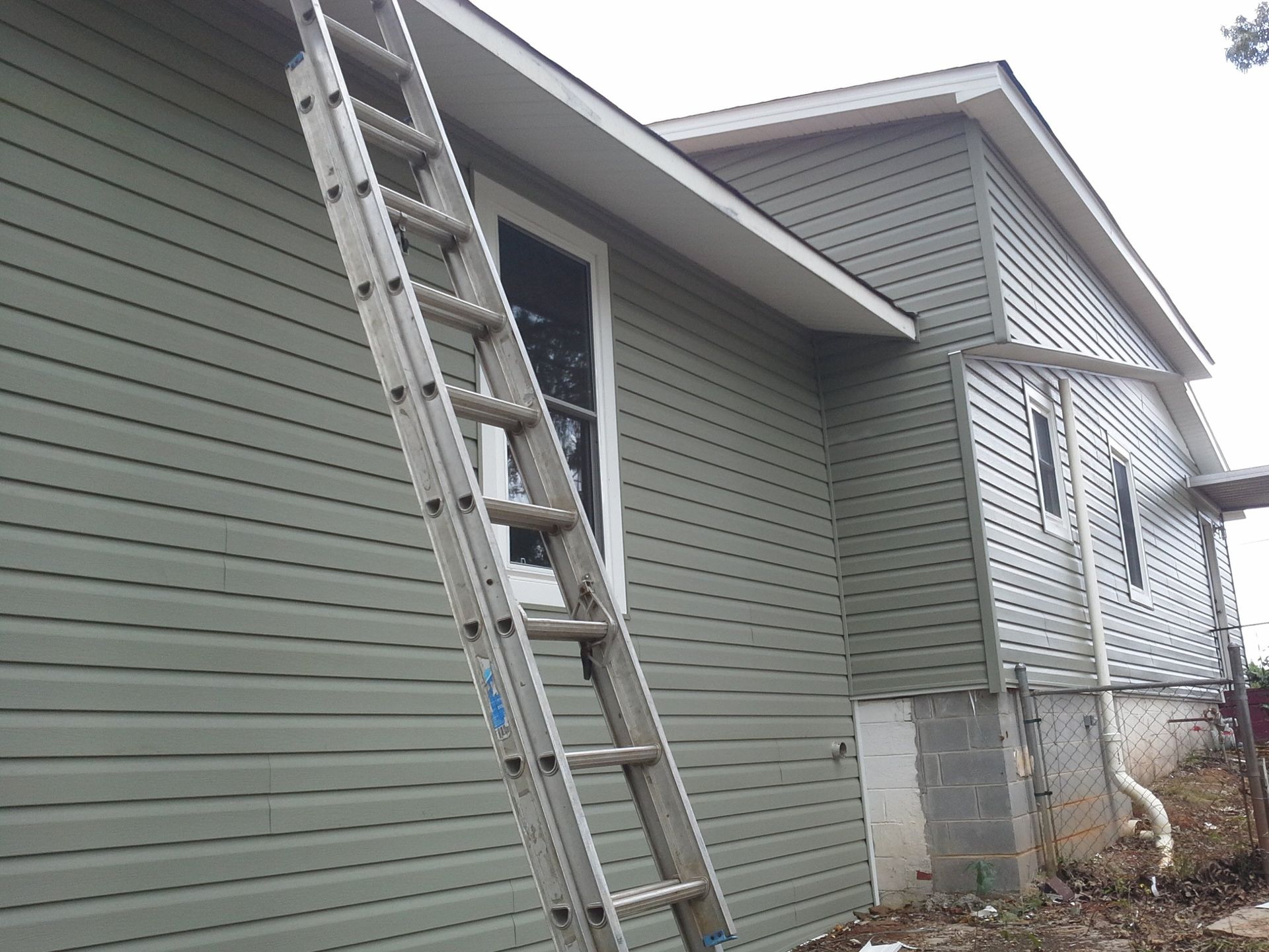 ladder going up back of house to complete gutter installation | Tuscaloosa, AL