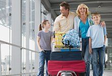 A family smiling as they walk through an airport