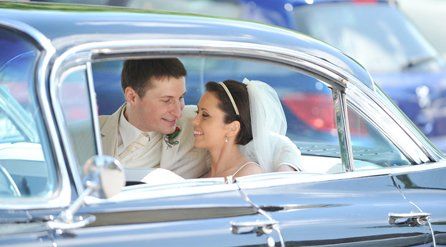 A newly-wed couple in the back of their wedding car