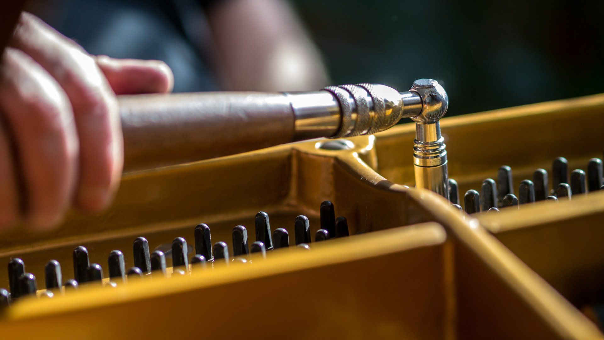 A person is working on a piano with a screwdriver.