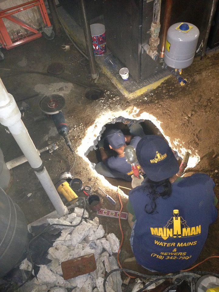 A man and a woman are working on a water heater in a basement.