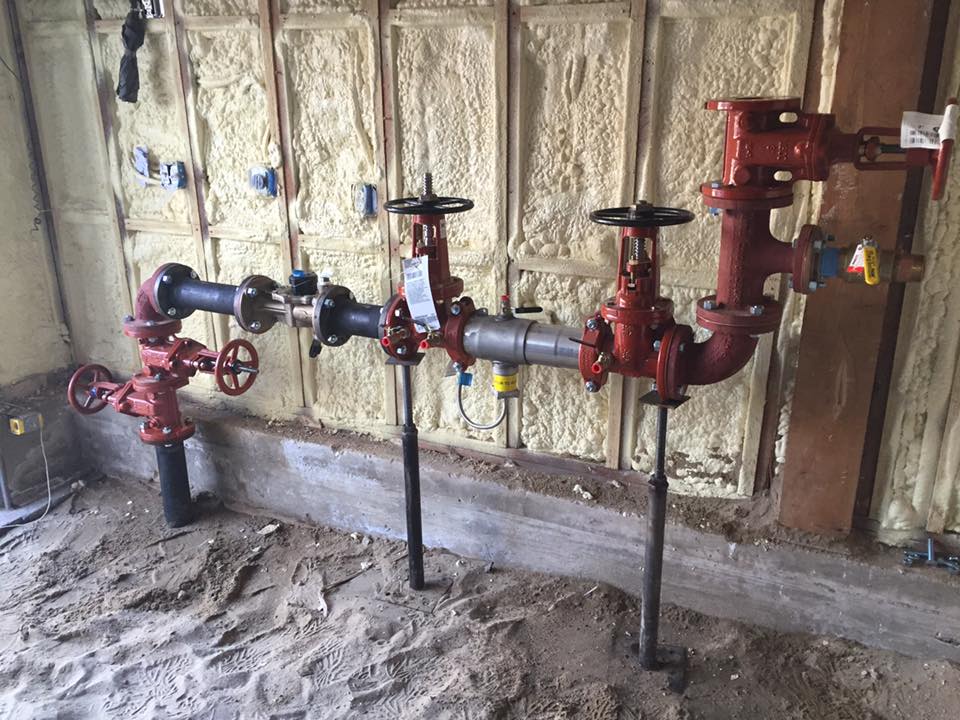 A bunch of pipes and valves are sitting on the ground in a room.