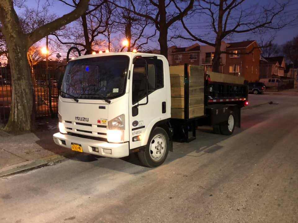 A white truck with a wooden bed is parked on the side of the road.