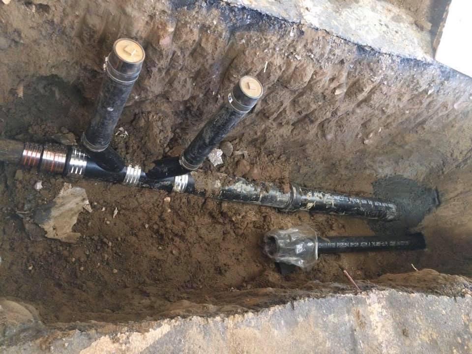 A bunch of pipes are laying in the dirt.