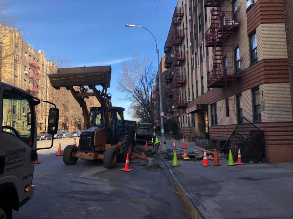 A bulldozer is driving down a street next to a building.