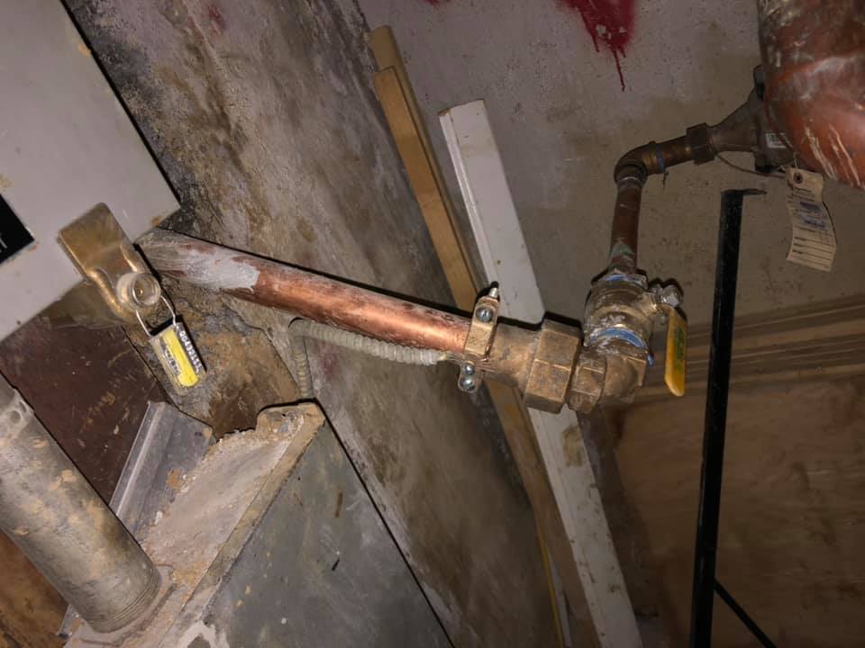 A close up of a copper pipe with a yellow valve attached to it.