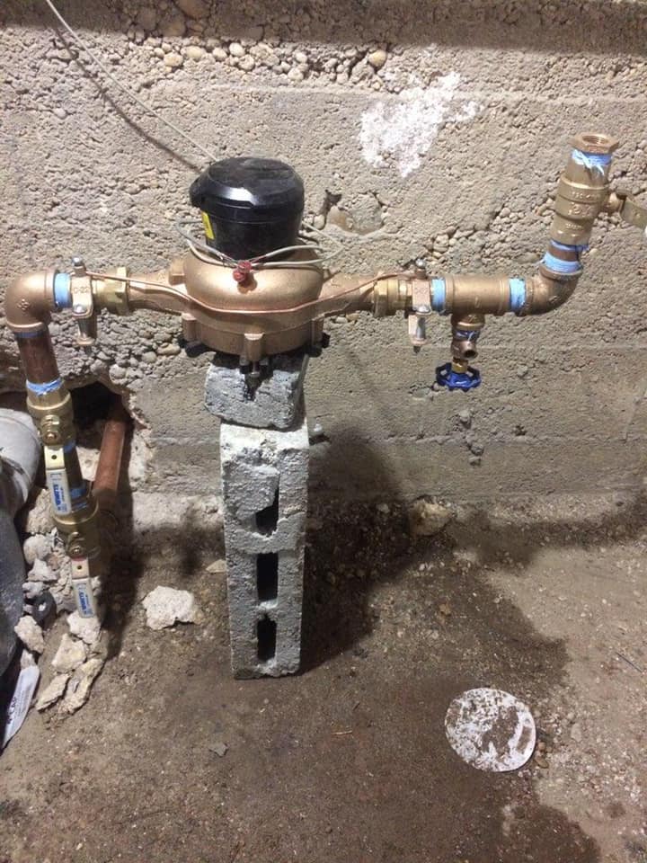 A water meter is sitting on top of a concrete block.