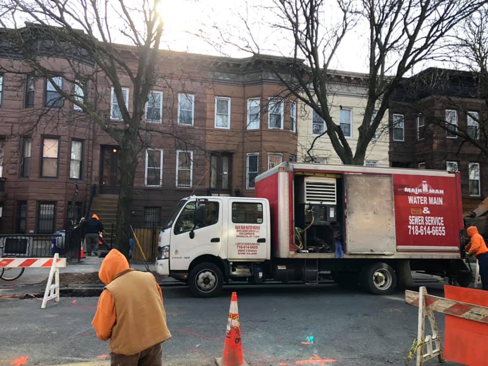 A construction truck is parked on the side of the road in front of a building.