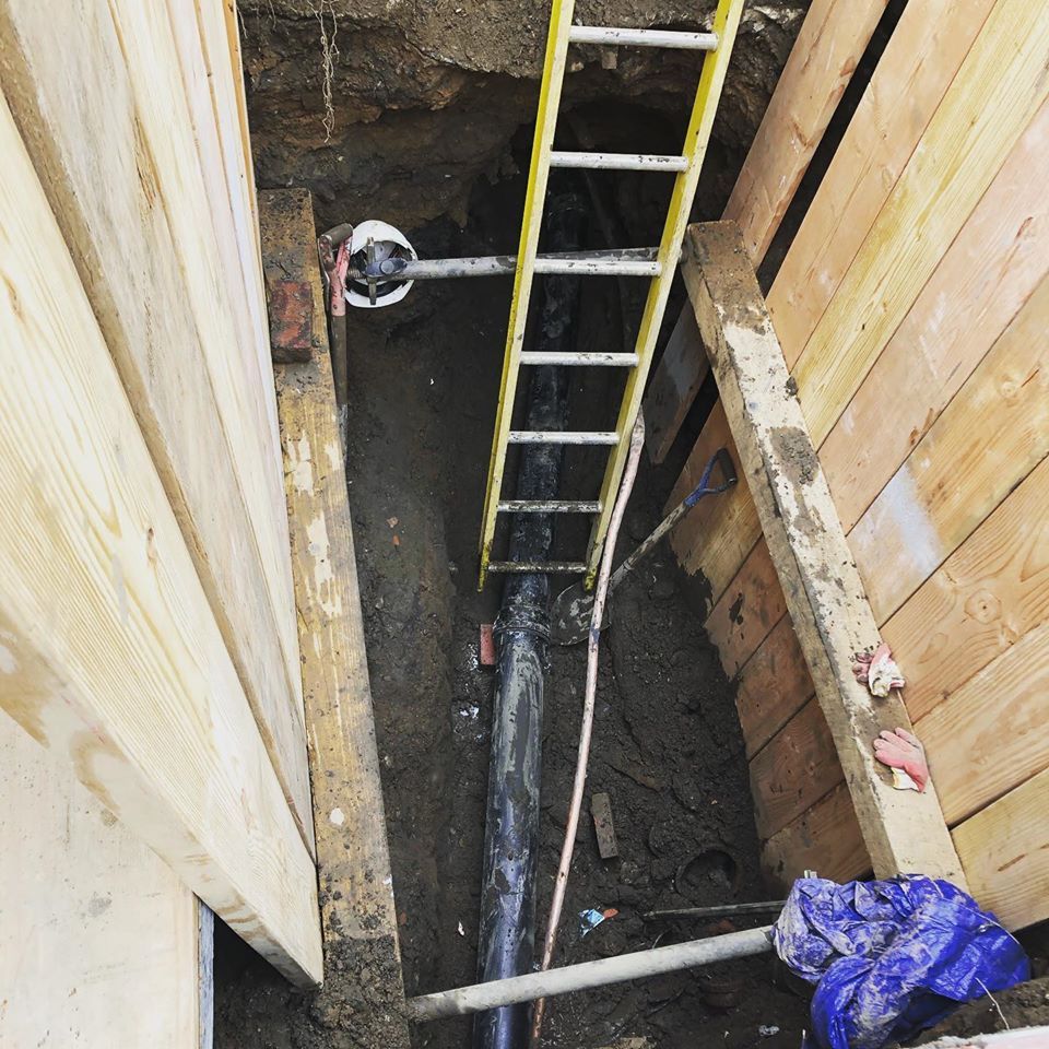 A ladder is in a hole next to a pipe