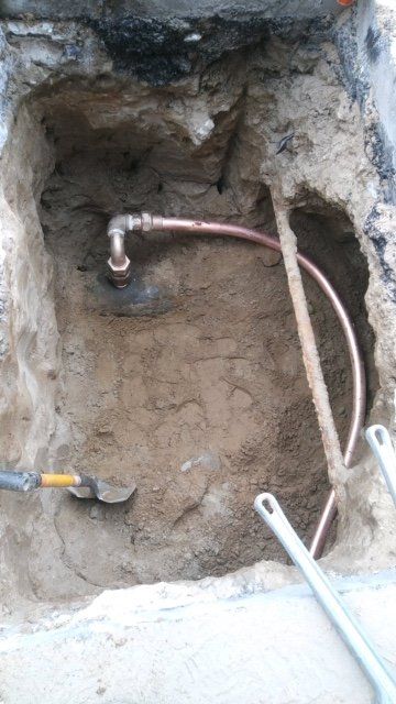A copper pipe is being installed in a hole in the ground.