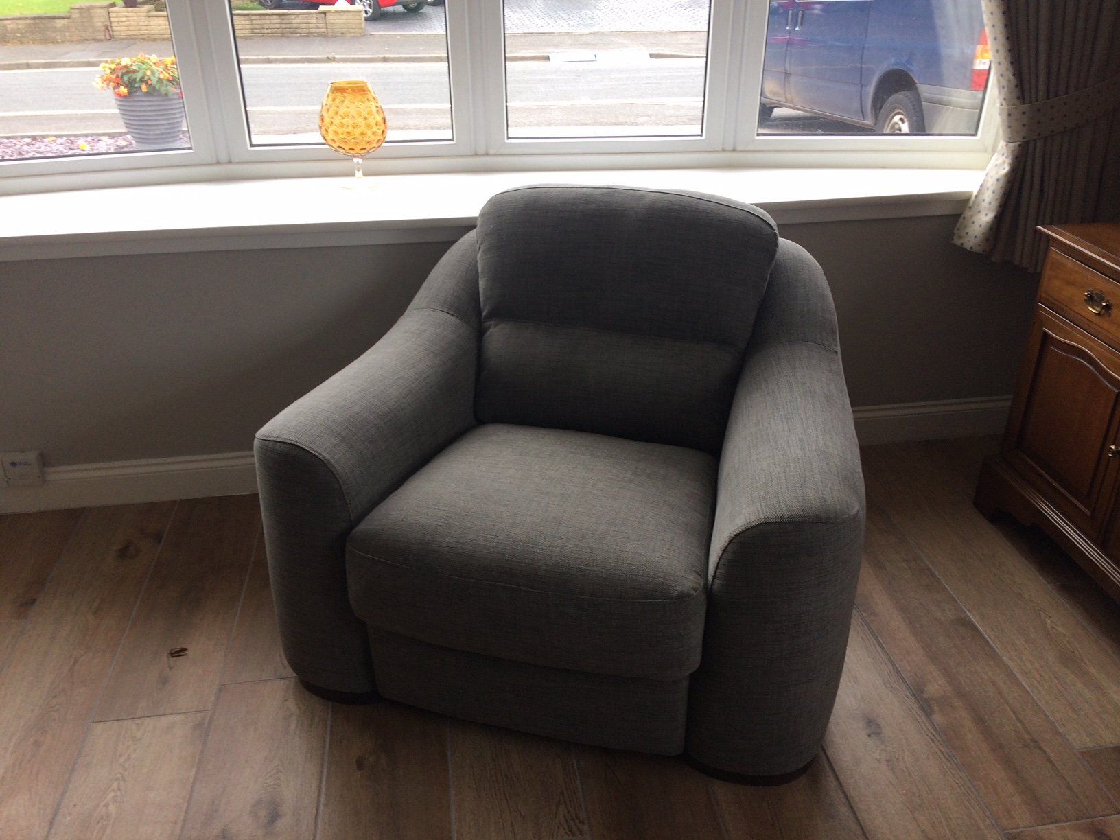 A dark coloured armchair beside a window