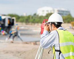 man in hardhat taking land survey