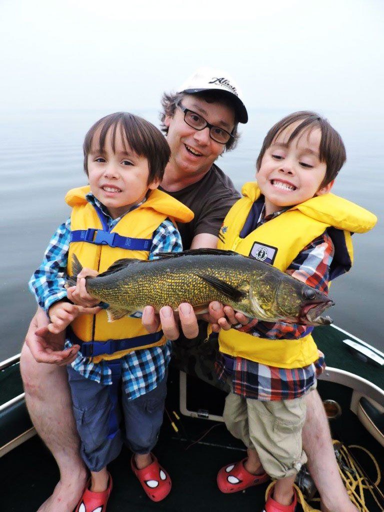 A photo of a man with two boys holding a freshly caught fish