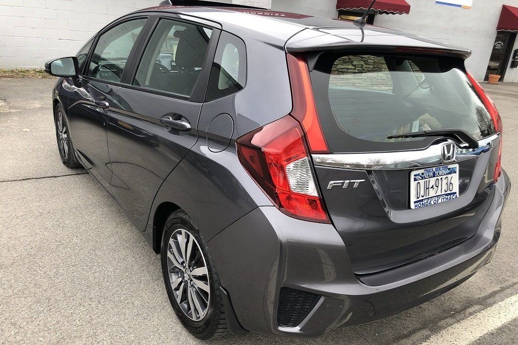 A gray honda fit is parked in a parking lot.