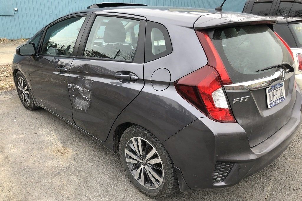 A gray honda fit is parked in a parking lot.