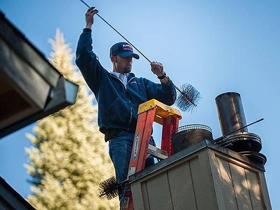 Man Cleaning Chimney  — Annandale, MN — SJ Roofing LLC