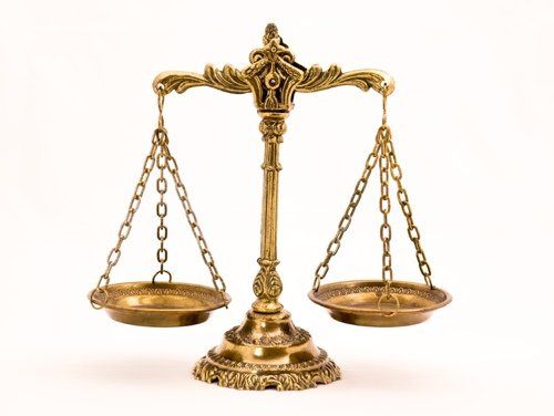 A brass scale of justice on a white background.