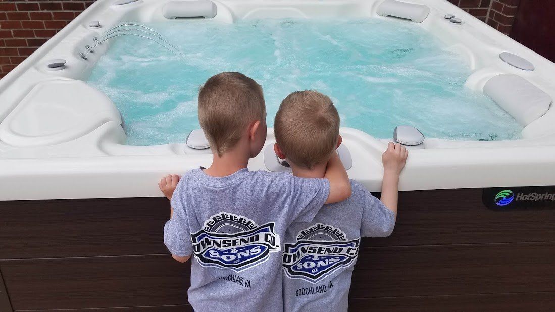 Two young boys are standing next to a hot tub.