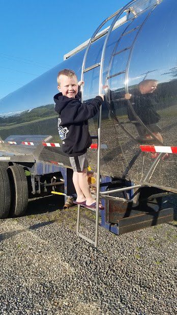 A young boy is standing on a ladder next to a truck.