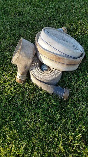 A fire hose is laying on top of a lush green field.