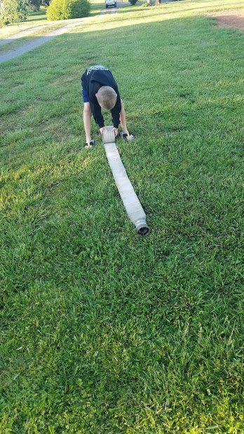 A young boy is playing with a hose in the grass.
