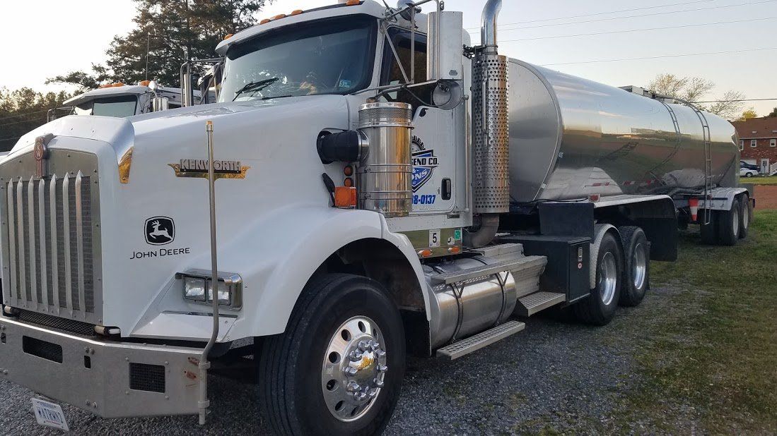 A large tanker truck is parked in a gravel lot.