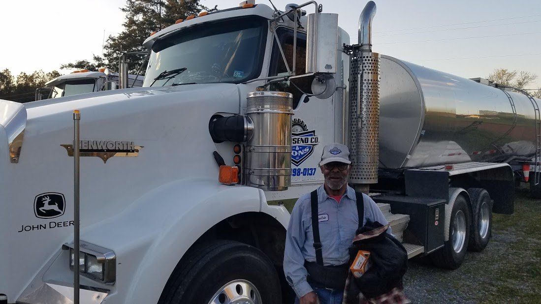 A man and a dog are standing in front of a large truck.