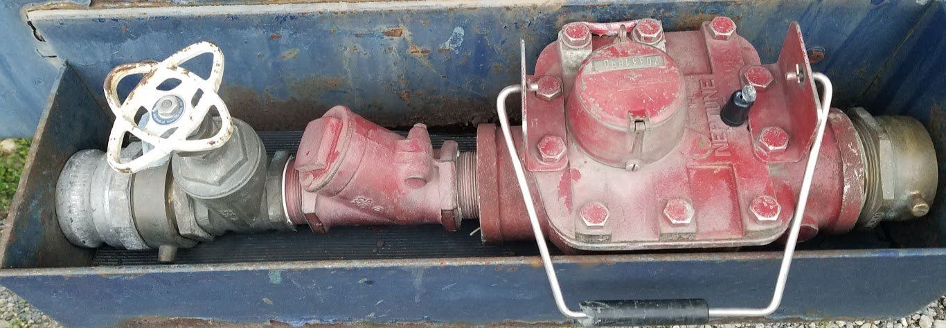 A red water meter is sitting in a metal box.
