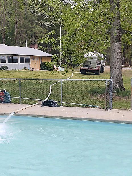 A swimming pool with a truck in the background and a house in the background.