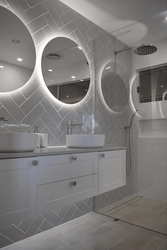 A bathroom with two sinks , two mirrors and a shower.
