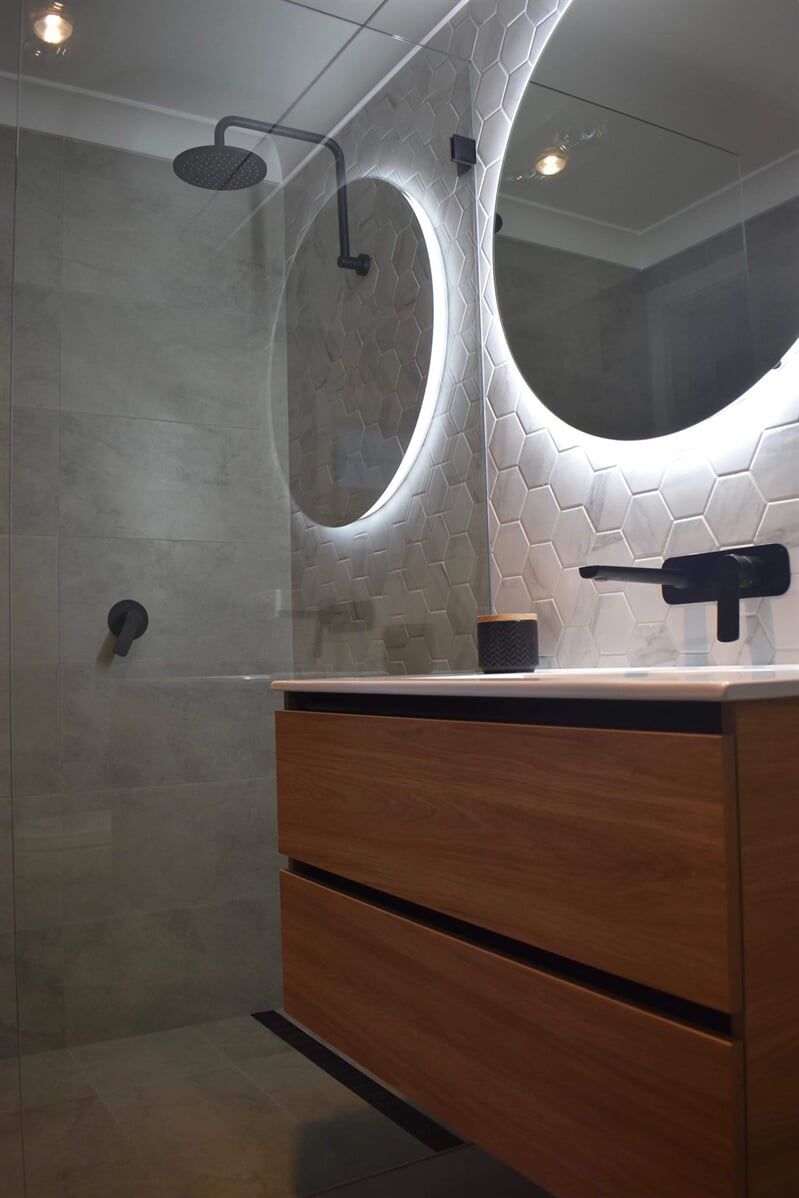 A bathroom with a sink , mirror and shower.